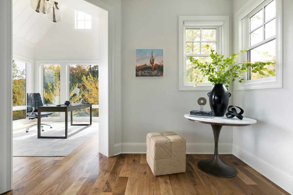 home office in lake home with white shiplap walls and large windows